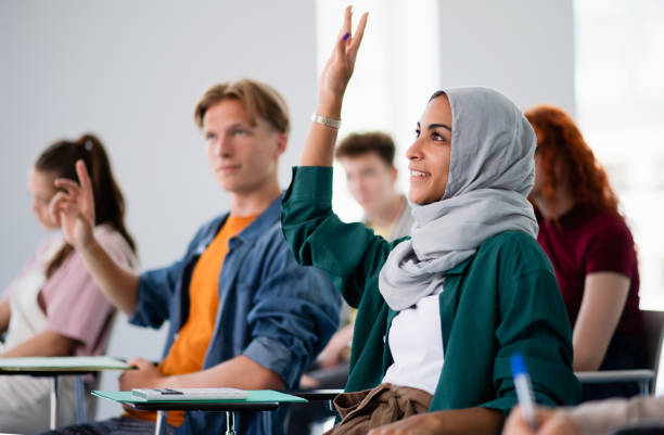 a group of university students sitting in classroom indoors, studying.